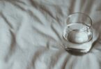 glass of water lying on a bed